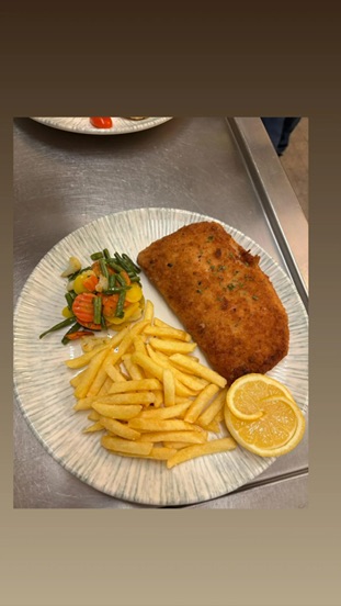 Paniertes Gericht mit Pommes frites, Gemüse und Zitrone
